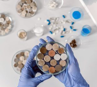 Cientista usando luvas examina amostras de solo em placas de Petri sobre uma bancada branca.